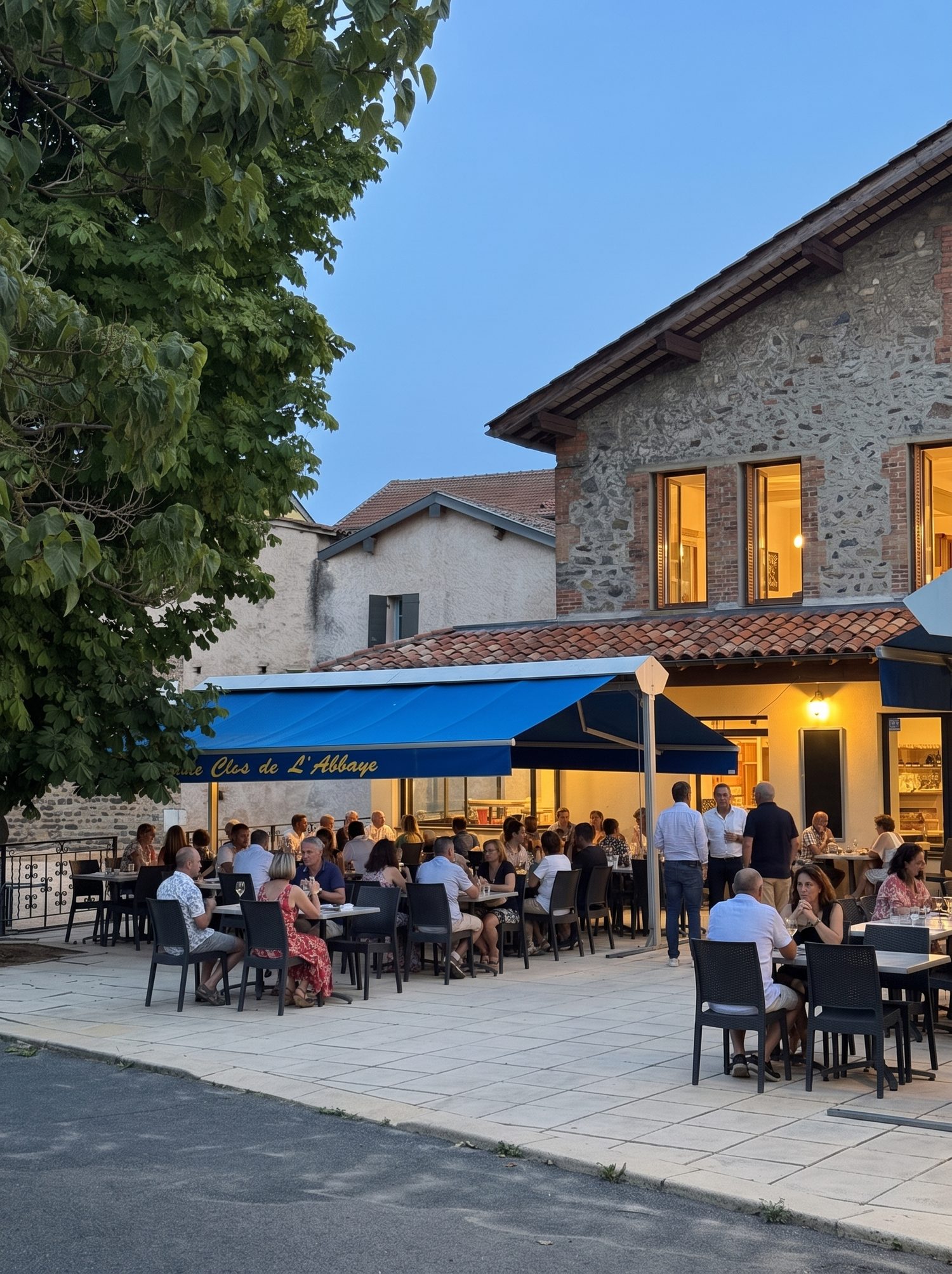 La terrasse du Clos de l'Abbaye un soir de privatisation, les tables occupées à la nuit tombante